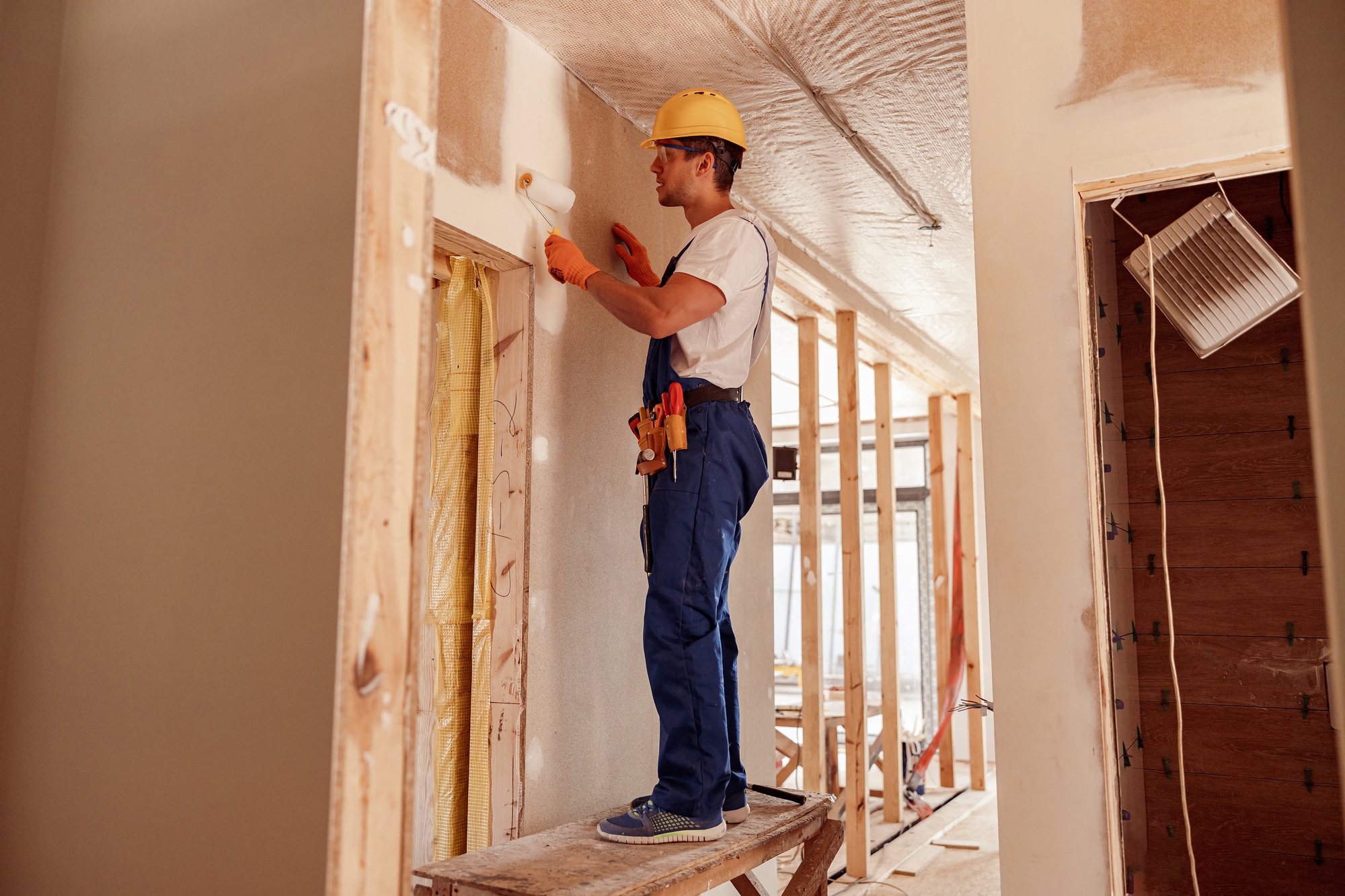 Inicio 5 Male builder painting wall in house under construction